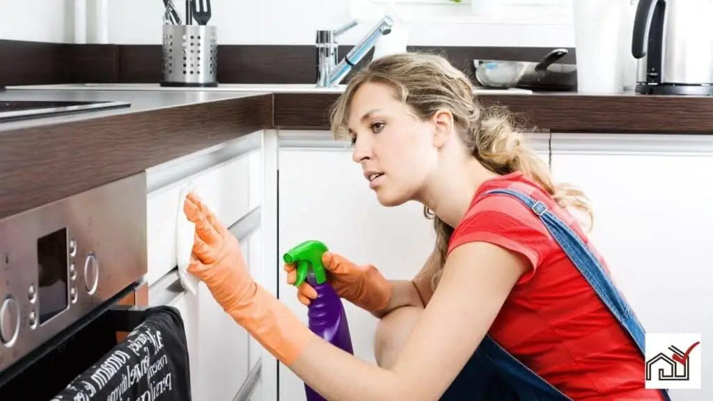Woman cleaning white kitchen cabinets