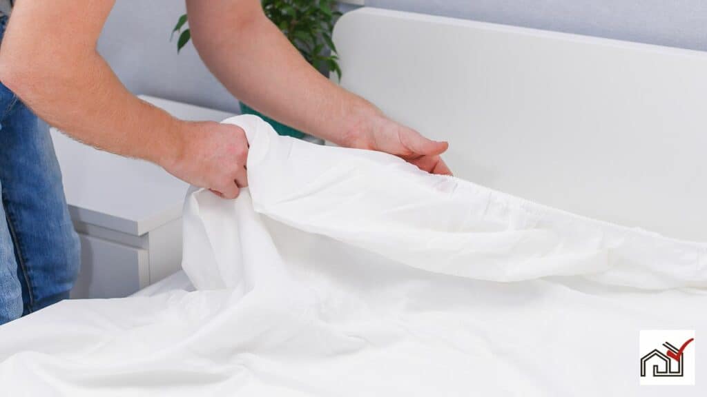 man putting linen sheet on bed